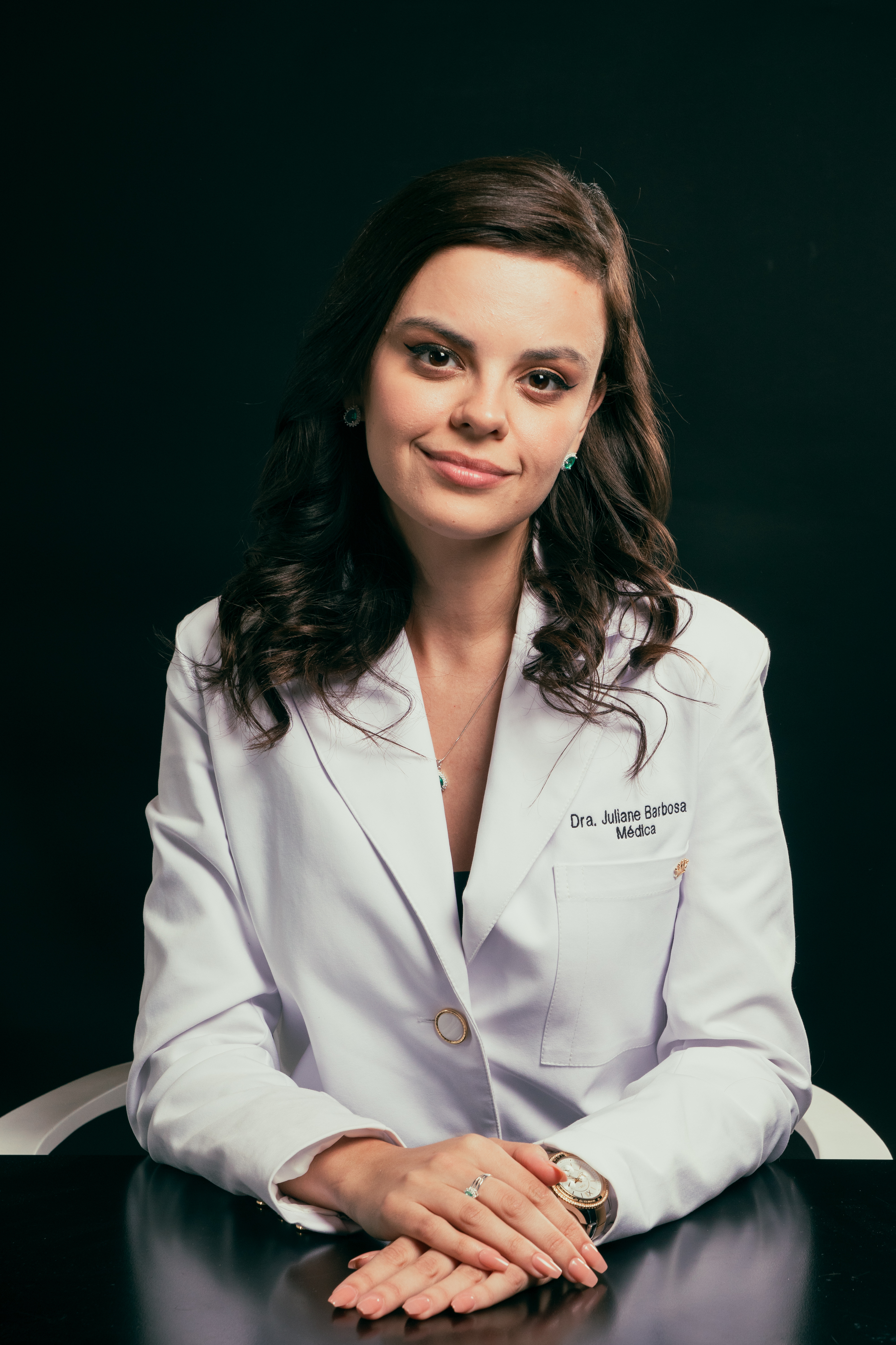 Dra. Juliane Barbosa sentada, de jaleco branco